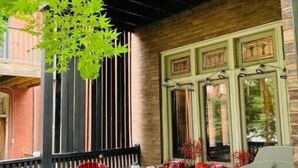 An outdoor patio with a table and chairs, a brick wall, and a window with decorative shutters. - 1905 Tudor Revival house in Historic Shaw (St. Louis)