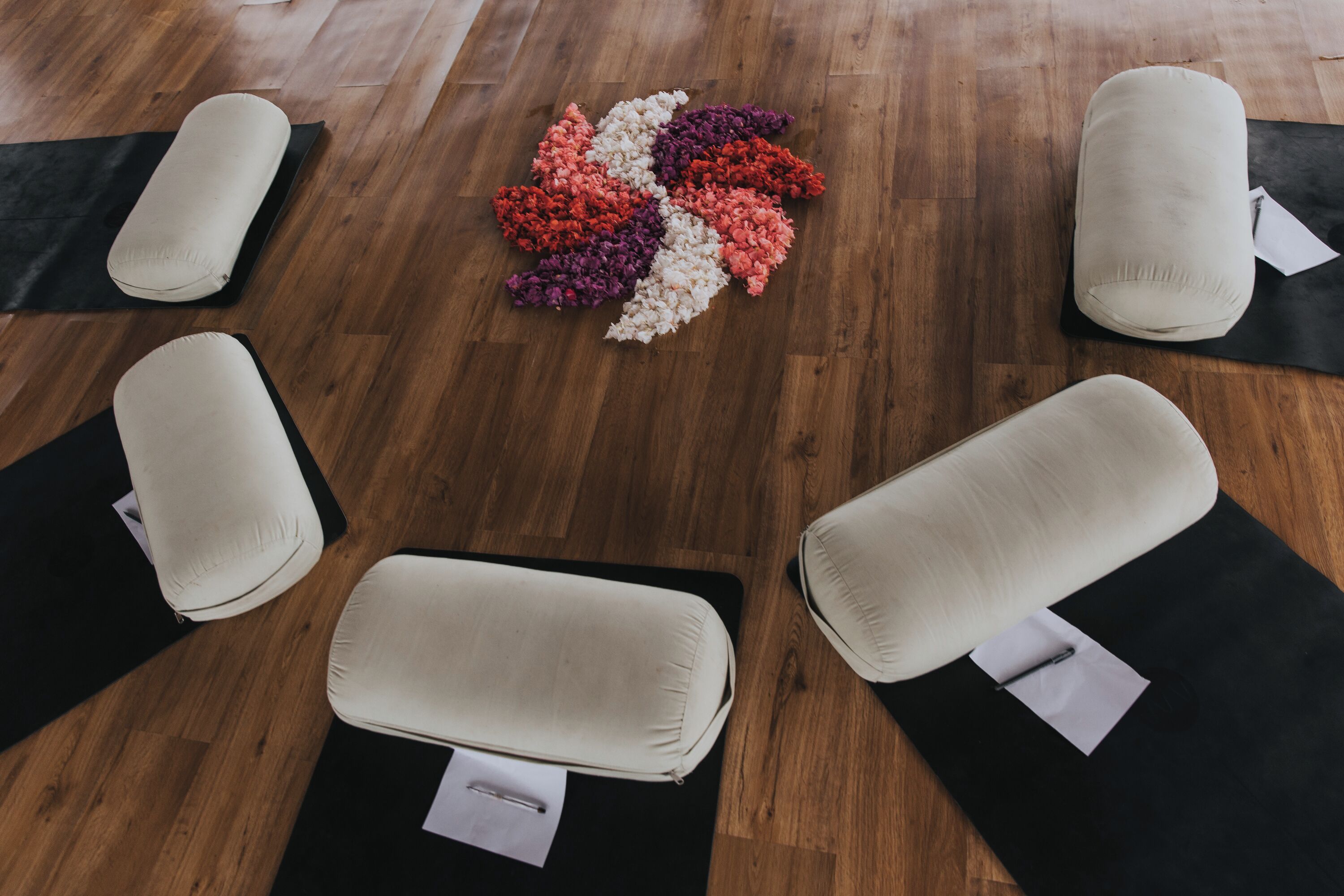 A room with four massage chairs on black mats, arranged in a square pattern on a wooden floor.