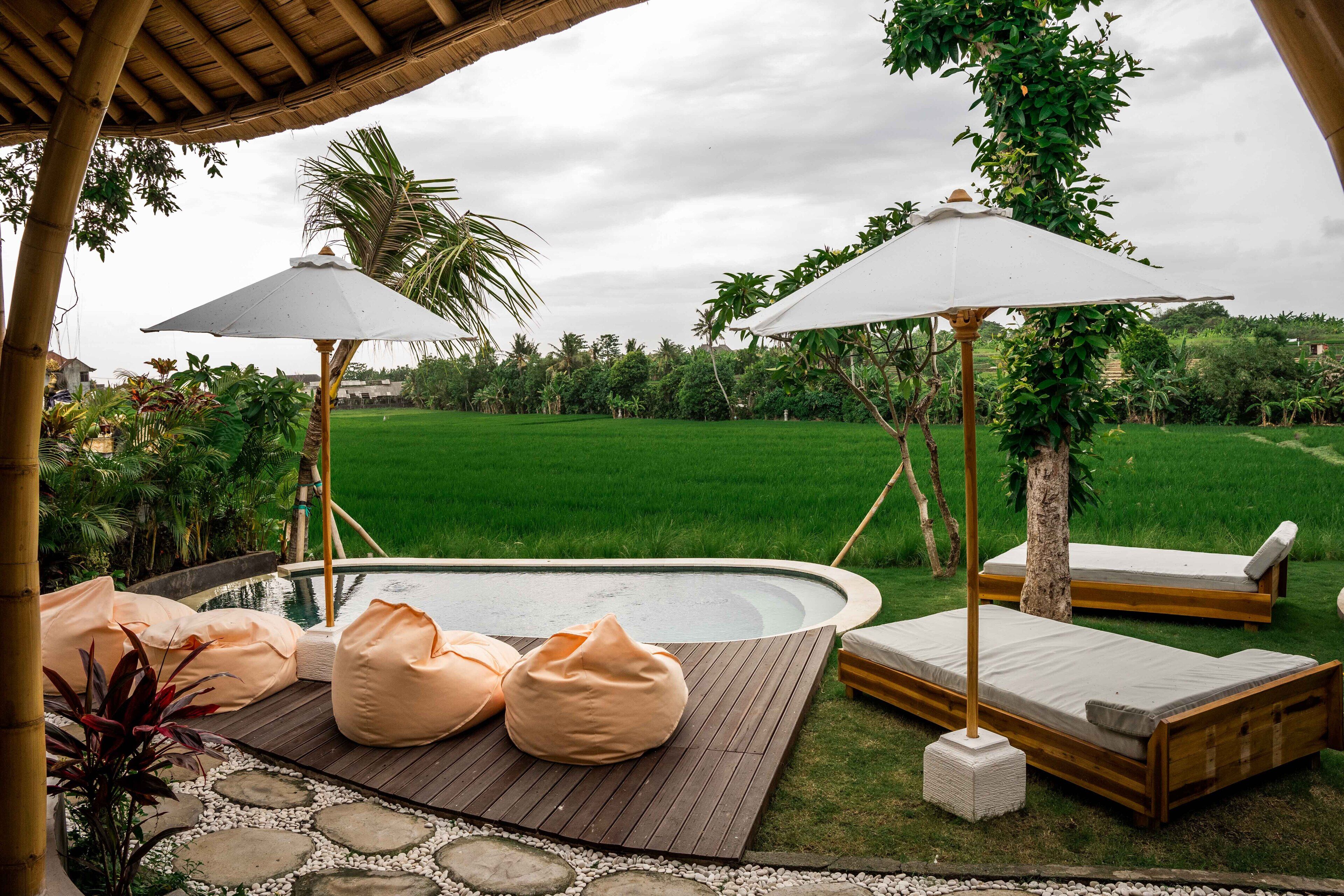 A poolside area with lounge chairs, bean bags, and umbrellas.