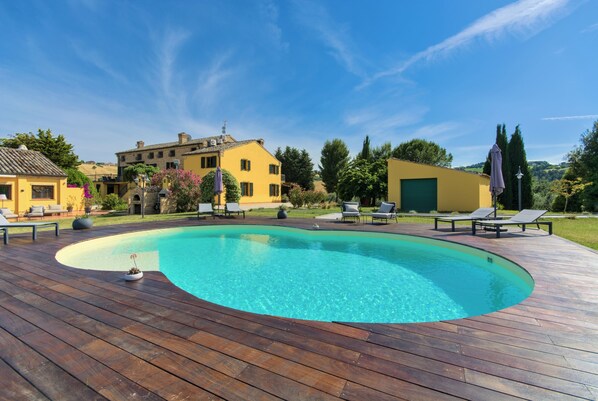 En säsongsöppen utomhuspool, parasoller och solstolar