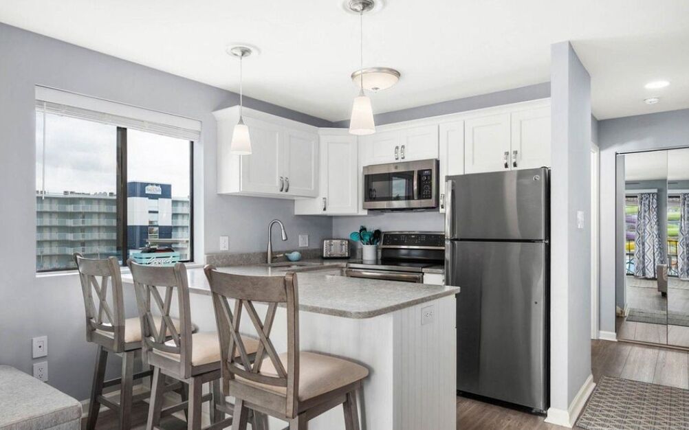 A modern kitchen with white cabinets, stainless steel appliances, and a central island with bar stools.