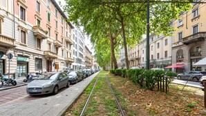 Una calle con coches aparcados, una vía de tranvía y edificios con balcones.