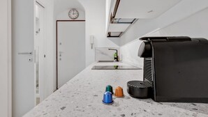 Una cocina moderna con una encimera, una cafetera y un reloj en la pared.