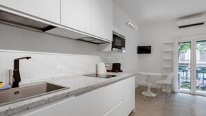 Una cocina moderna con armarios blancos, un lavamanos integrado y una pequeña zona de comedor con mesa y sillas.