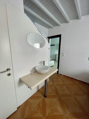 A modern bathroom with a white vanity, a round mirror, and a vessel sink. - Appartamento con 2camere da letto (Mikonos)