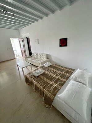 A room with a bed, a sofa, a table, and a door leading outside. - Appartamento con 2camere da letto (Mikonos)
