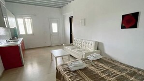A spacious room with a bed, a white sofa, a small table, and a red cabinet.