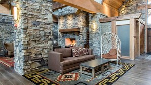 Una sala de estar acogedora con chimenea de piedra, un sofá, una mesa de centro y un sillón colgante.