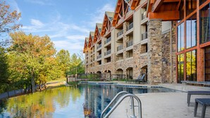 Un hotel con fachada de piedra, varios balcones y una piscina.