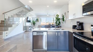 A modern kitchen with a dishwasher, stove, and coffee maker. - Modern Beachfront Retreat 2 King Suites + (Puerto Peñasco)