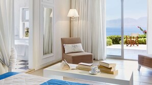 Una habitación con vista al mar, un sofá, una mesita de café con libros y una taza, y una lámpara.