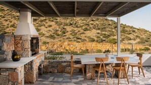 Un patio exterior con piso de piedra, una chimenea de piedra y una mesa con sillas.