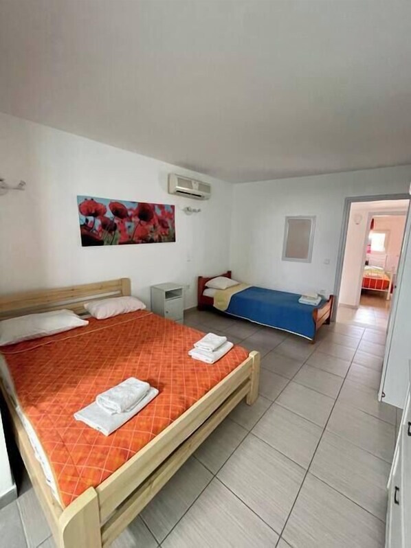 A bedroom with two beds, a nightstand, a small table, and a painting on the wall.