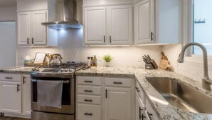 A modern kitchen with white cabinets, a stainless steel range, and a granite countertop. - NEW, Stunning Flagstaff Home w/ Deck and Firepit (Flagstaff)