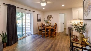 A spacious dining area with a wooden table and chairs, a ceiling fan, and a view through glass doors to an outdoor patio. - NEW, Stunning Flagstaff Home w/ Deck and Firepit (Flagstaff)