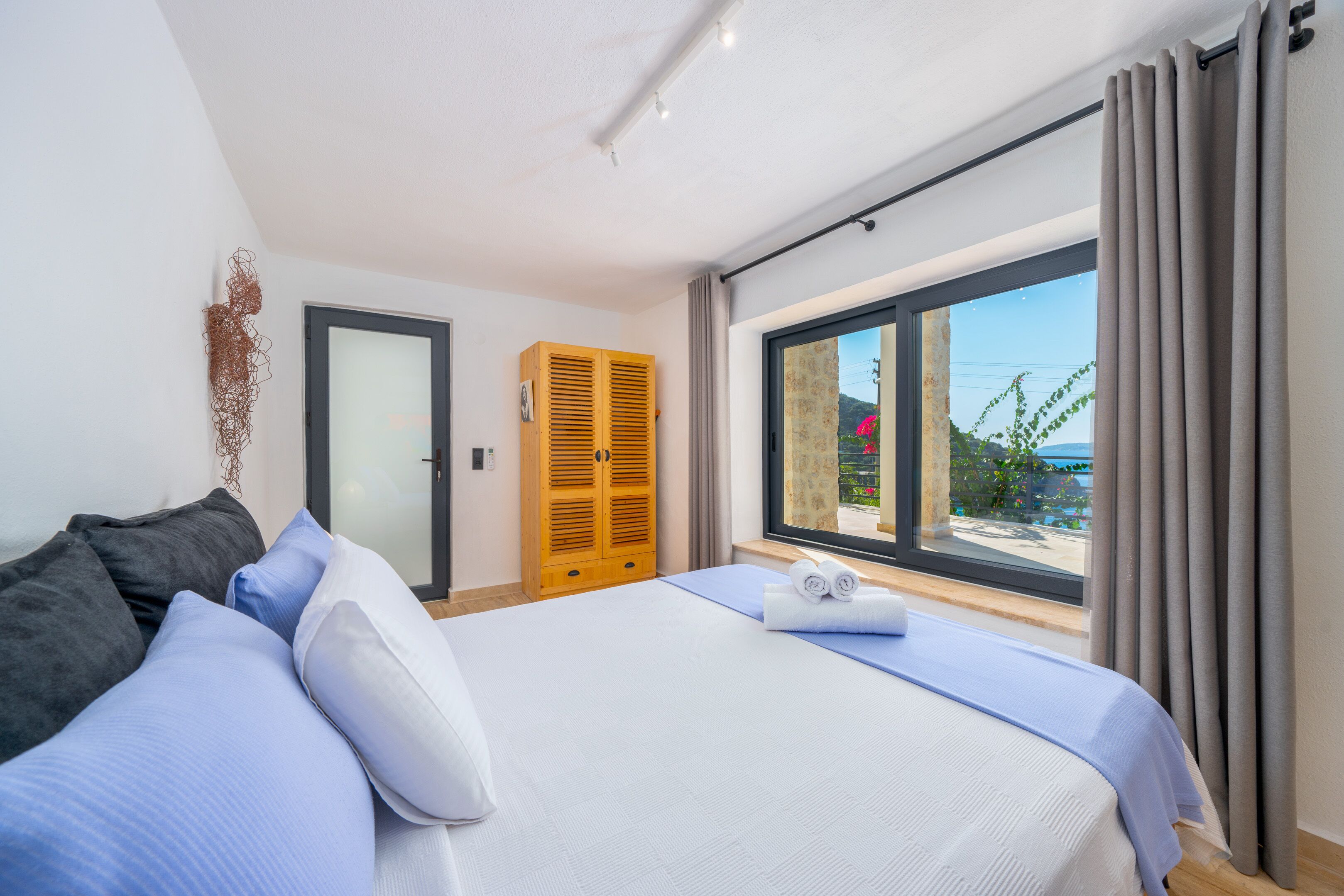 Un dormitorio moderno con una cama grande, un armario de madera y vistas al exterior.