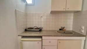 A compact kitchen with white cabinets, a small window, and a tiled backsplash. - Two-room apartment for 4 people, with (Mikonos)