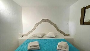 A single bed with a blue bedspread, two white pillows, and two folded white towels. - Two-room apartment for 4 people, with (Mikonos)