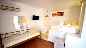 Un dormitorio con cama, mesita de noche, espejo, televisor y aire acondicionado instalado en la pared.