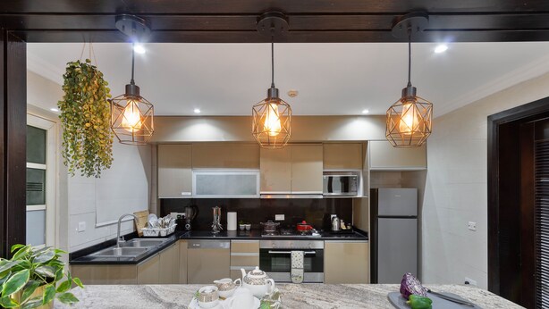 Cozinha moderna com bancadas de granito, eletrodomésticos de aço inoxidável e luminárias pendentes.