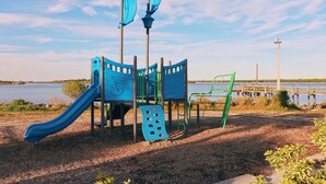 Ein Spielplatz mit Rutsche und Klettergerüsten in der Nähe von Wasser.