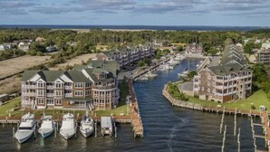 A waterfront hotel with multiple buildings, a marina with several boats docked, and a view of the ocean.