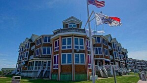 A multi-story hotel with a central tower, a flagpole with an American flag, and a beachside location.
