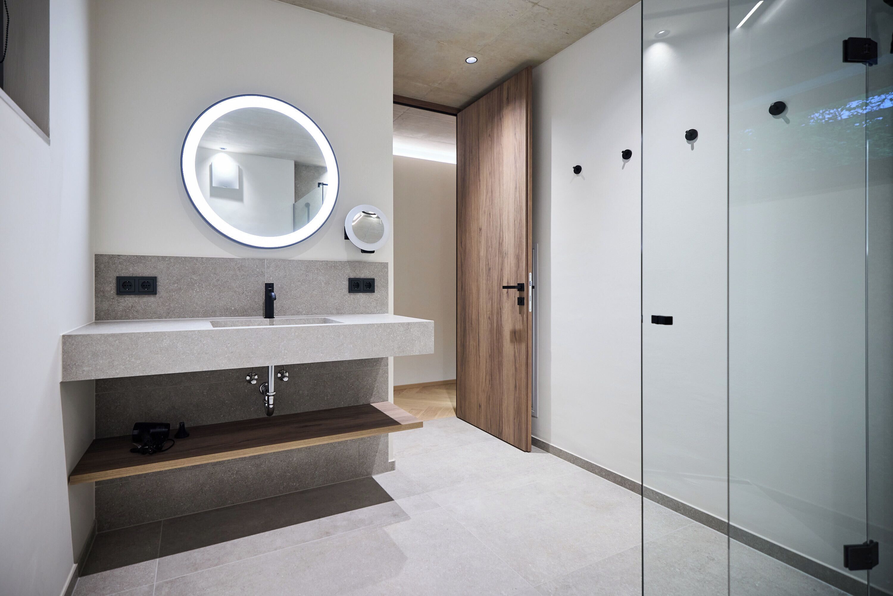 Une salle de bain moderne avec un grand miroir, un lavabo et une porte en bois.