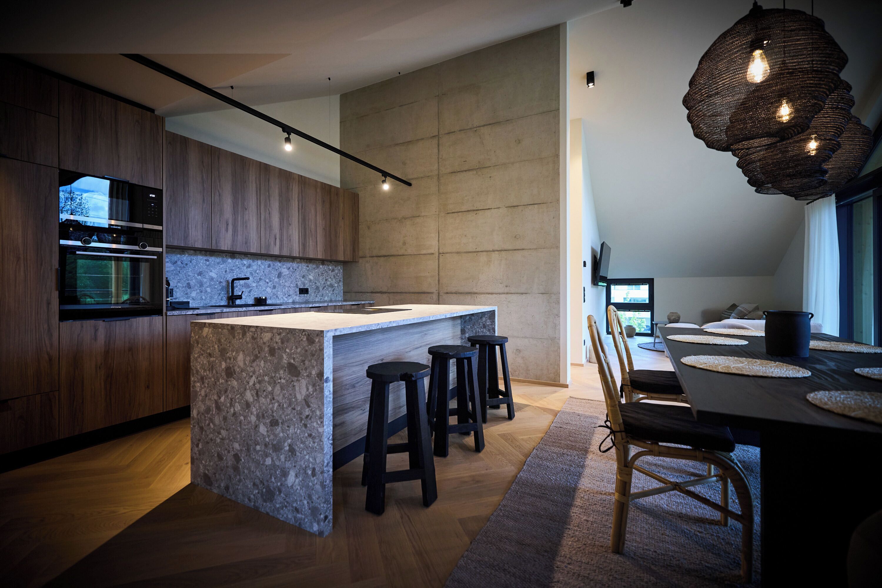 A modern kitchen with a large island, wooden cabinets, and a built-in oven.
