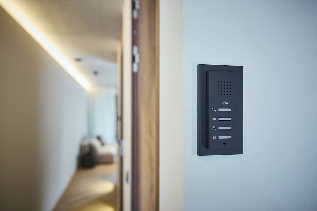 A modern wall-mounted control panel with a minimalist design, featuring a series of buttons and a small display.