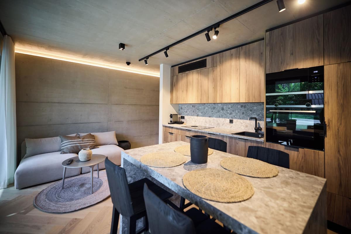 A modern kitchen with a central island, built-in appliances, and a dining area with a sofa and coffee table.