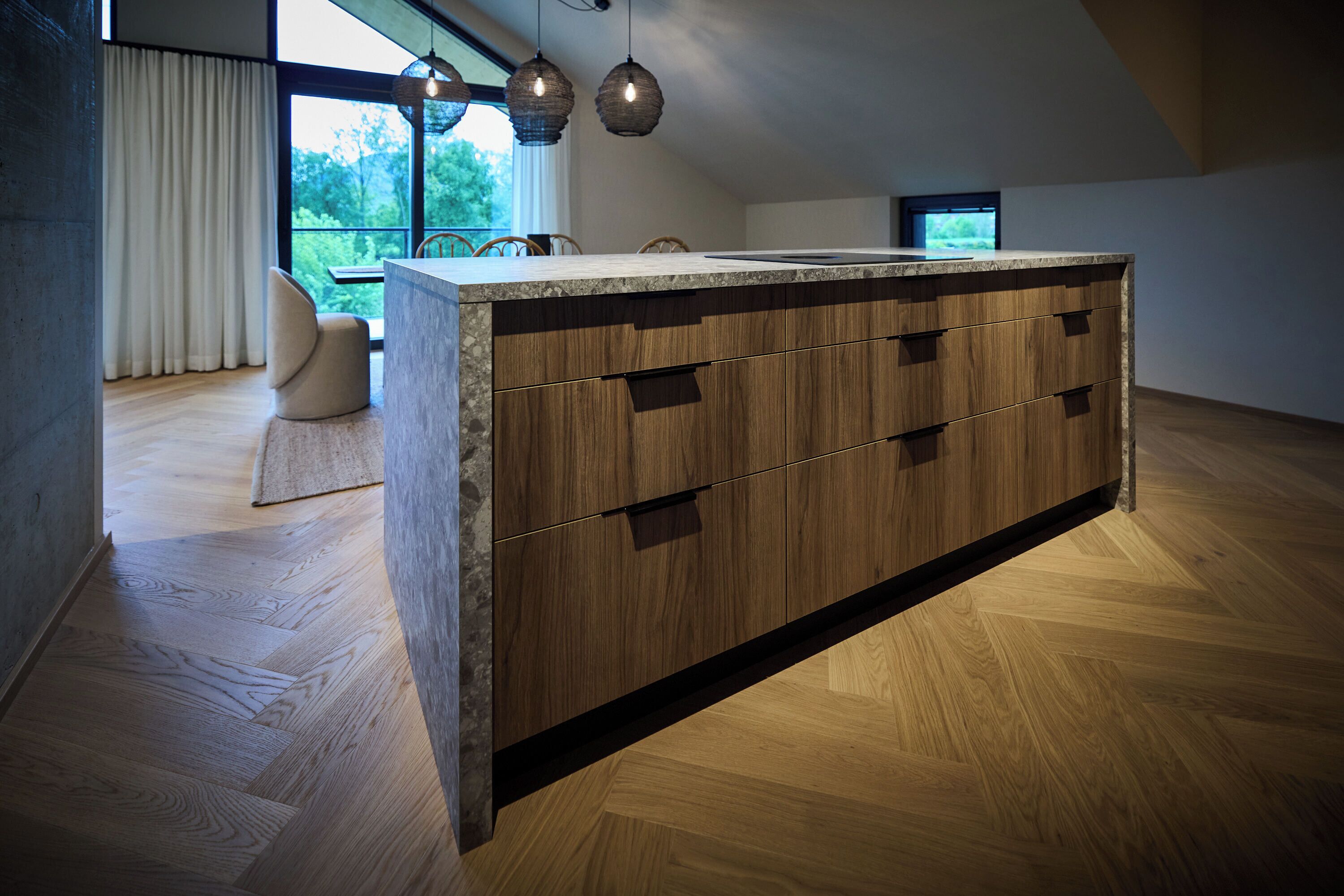 Una cucina moderna con isola centrale, mobili in legno e illuminazione a sospensione.