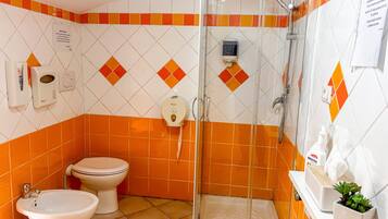 A bathroom with a shower, toilet, bidet, and a sink.