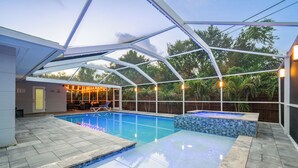 Ein überdachter Pool mit Glasdach, umgeben von Steinfliesen und einer Holzterrasse.