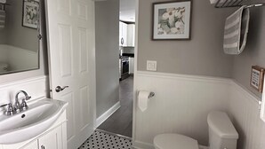 Un bany amb un lavabo blanc, vàter i sòl de rajola.