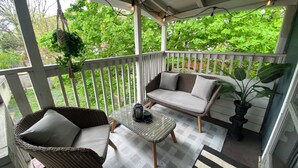 A covered porch with wicker furniture, a cushioned bench, and a potted plant. - Cozy apartment right in Downtown Downers Grove (Downers Grove)