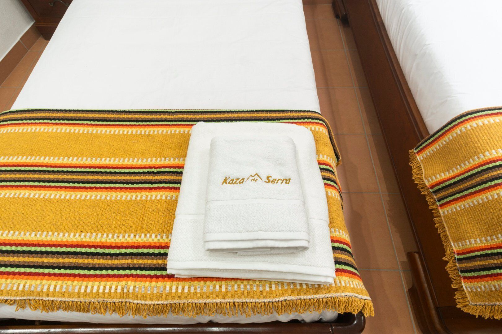 Ein Bett mit einem weißen Handtuch und einer bunten, gestreiften Decke.