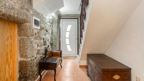 Passatge amb paret de pedra, porta de fusta, una banca i un arca de calaixos.