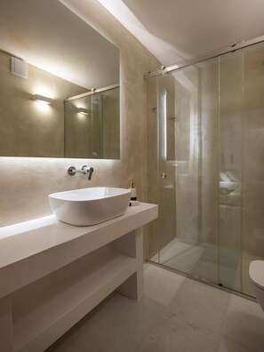 A modern bathroom with a large white sink, a mirror, and a glass shower enclosure.