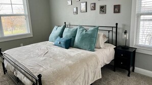 Une chambre à coucher avec un lit, une table de chevet, une lampe et un mur orné de tableaux.