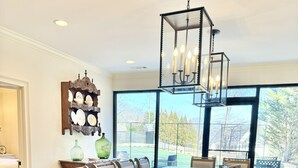 Un espace repas comprenant un grand îlot central, quatre chaises rembourrées, un lustre et un élément décoratif fixé au mur.