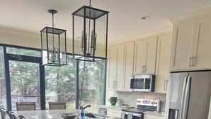 Une cuisine moderne dotée d’un grand îlot central, de chaises en bois et offrant une vue sur l’extérieur.