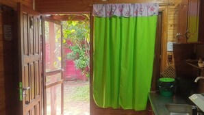 A wooden interior with a kitchen area, including a sink, cabinets, and a green curtain. - Bungalows El Pindó (Colonia Alberdi)