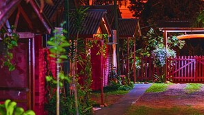 A pathway leading through a garden with wooden structures and a red gate. - Bungalows El Pindó (Colonia Alberdi)