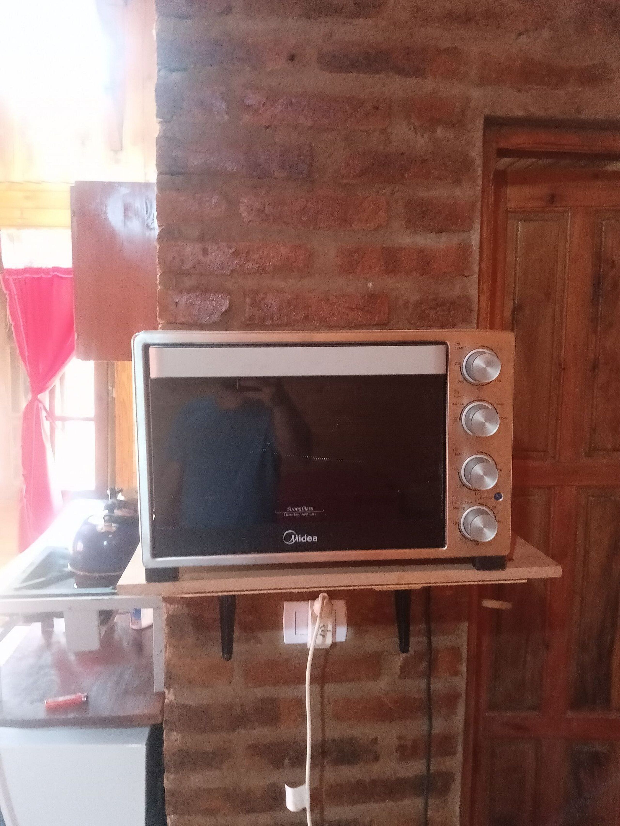 A microwave oven on a brick wall shelf in a kitchen.
