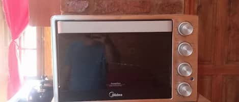 A microwave oven on a brick wall shelf in a kitchen.