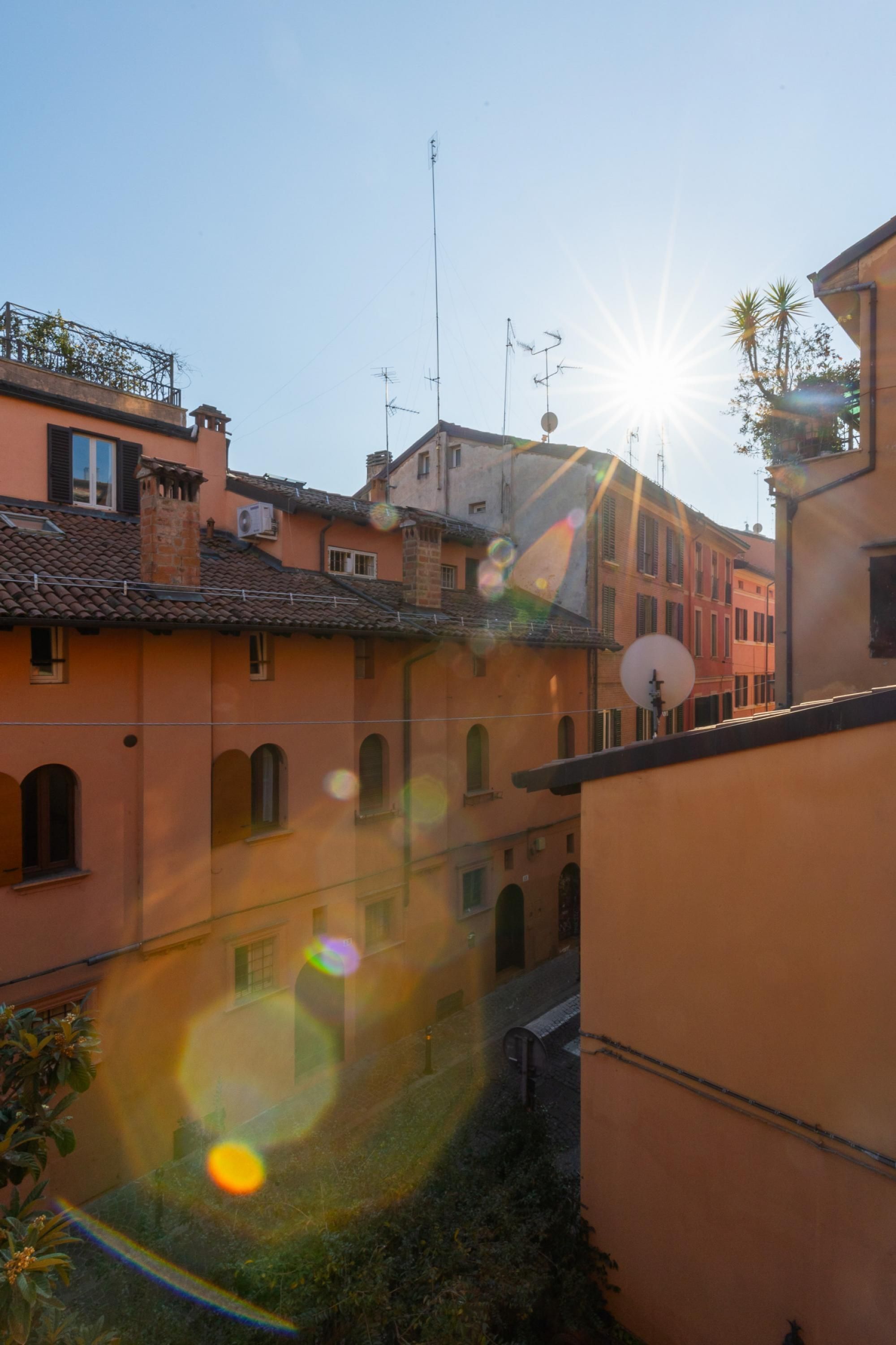 A courtyard with buildings, a satellite dish, and a clear sky.
