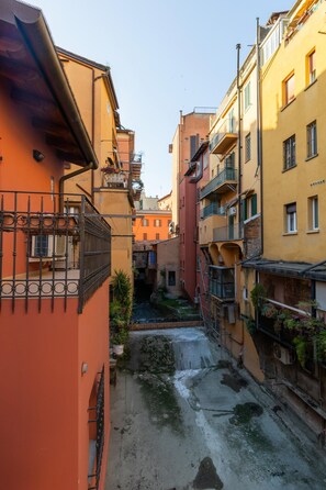 A narrow alleyway between buildings with balconies and air conditioning units. - White Daisy Apartment by Wonderful Italy (Bologna)