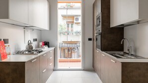 A modern kitchen with a central island, stainless steel appliances, and a view to an outdoor balcony. - White Daisy Apartment by Wonderful Italy (Bologna)