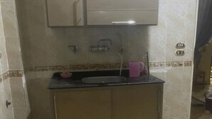 A small kitchen with a sink, a cabinet above the sink, and a tiled floor.